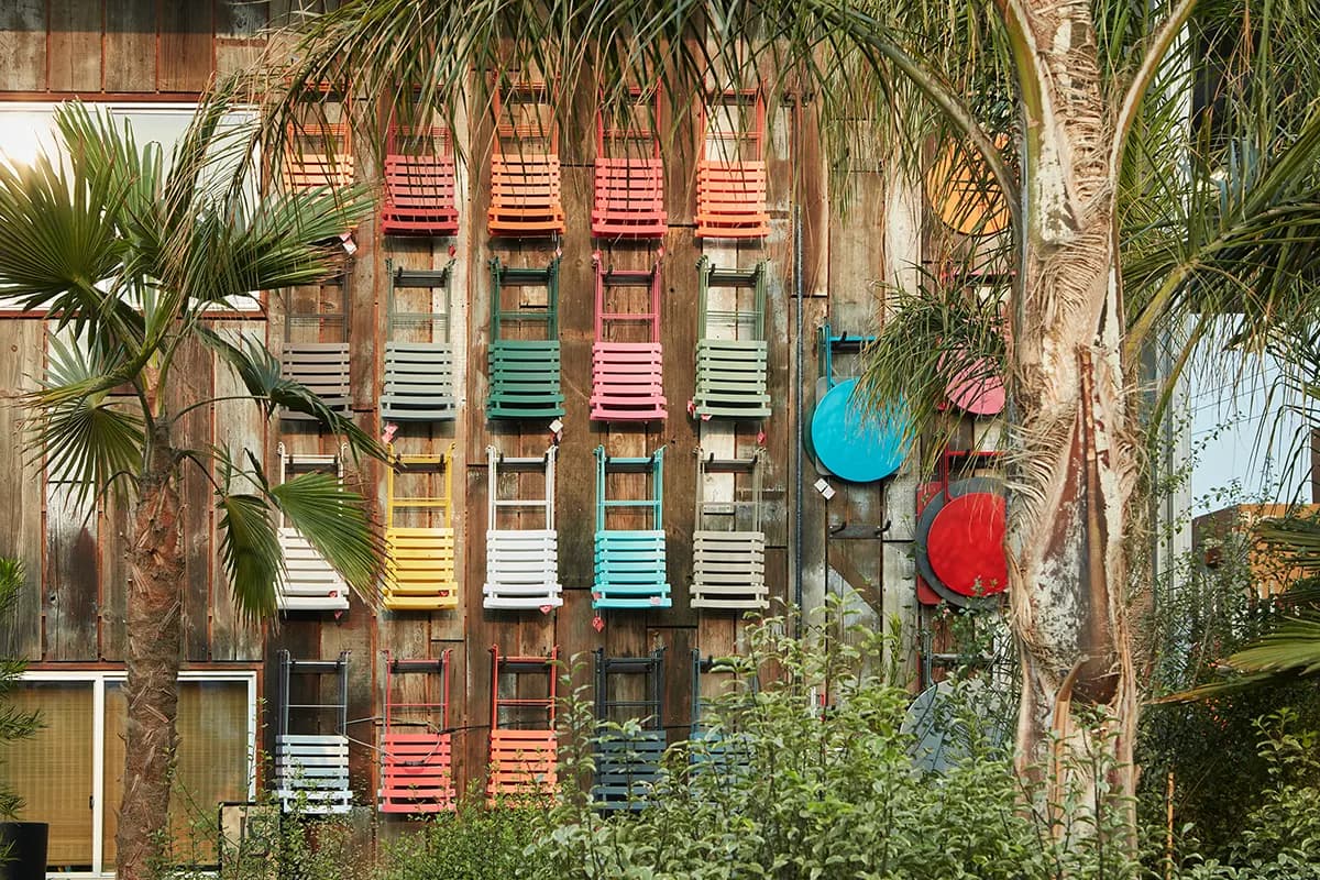 Colorful Fermob garden furniture at Flora Grubb Gardens displayed outdoors, surrounded plants and trees.